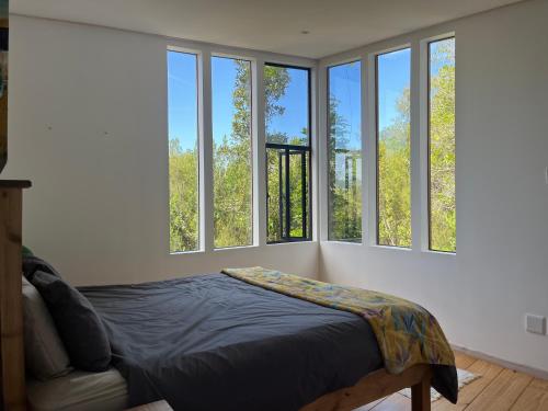 a bedroom with four windows and a bed in it at FireFly Starry Woods Cabin in Keurboomstrand