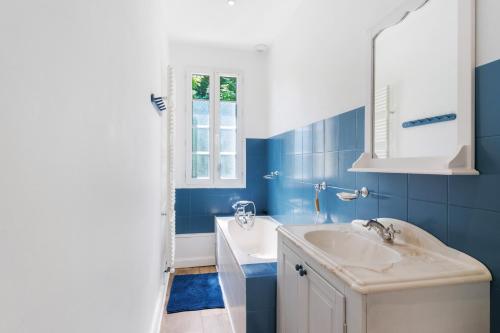 a blue bathroom with a sink and a tub at Chambres D'hôtes Chapetit in Saint-Denis-de-Pile