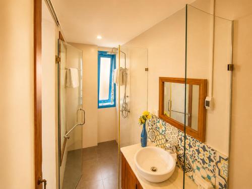 a bathroom with a sink and a glass shower at Metta Living Hoi An in Thanh Ðông (1)