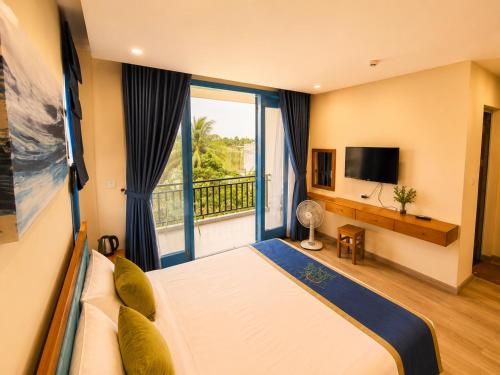 a bedroom with a bed and a balcony with a television at Metta Living Hoi An in Thanh Ðông (1)