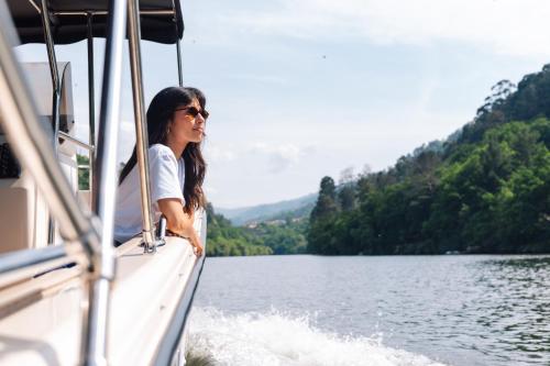 a woman standing on the side of a boat on a lake at Douro Royal Valley Hotel & Spa in Riba Douro