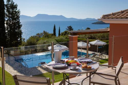 a patio with a table and chairs next to a pool at EOS Luxury Villa in Nydri
