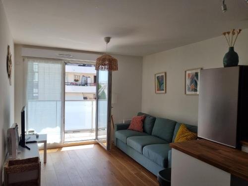 a living room with a blue couch and a sliding glass door at T2 Suresnes Proche La Défense Paris Parking Fibre in Suresnes