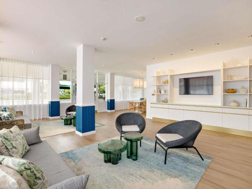 a living room with two chairs and a tv at Mercure Cairns in Cairns