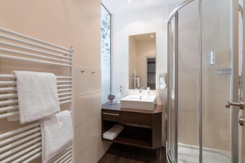 a white bathroom with a sink and a shower at Seehotel Vinzenz in Velden am Wörthersee