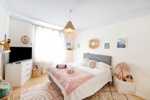 a white bedroom with a bed and a tv at Maison Cosy Bohème Chic Biarritz in Biarritz
