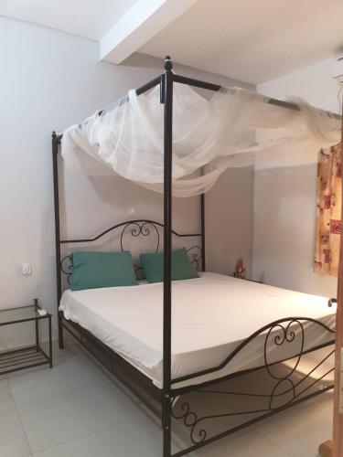 a bedroom with a black canopy bed with white sheets at Lasofia in Mbodiène