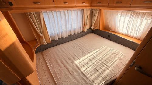 a small bed in the back of an rv at Przyczepy Kempingowe CHAŁUPY 6, KITE CREW in Chałupy