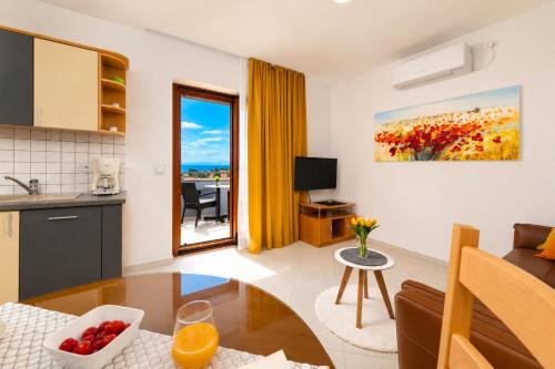 a living room with a table and a kitchen at Apartments Kvarner in Malinska
