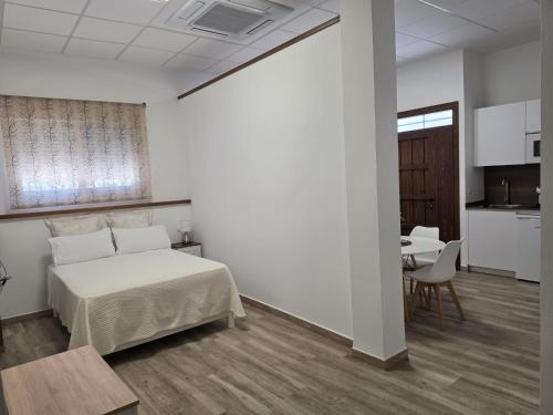 a bedroom with a bed and a table and a kitchen at Loft Plaza in Hornachuelos