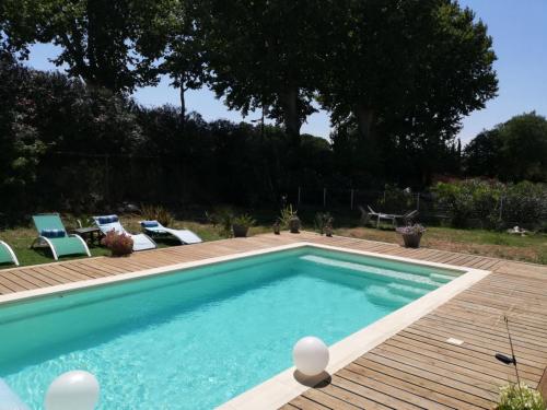 a swimming pool with chairs and a wooden deck at La Salamandre 66 in Saint-Génis