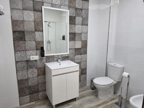 a bathroom with a toilet and a sink and a mirror at Loft Plaza in Hornachuelos
