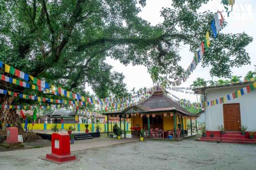 a temple with colorful flags hanging from a tree at StayVista at The Sahib's Bungalow with BBQ & Bonfire in Kālchīni