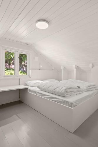 a white bedroom with a bed and a window at Hagehuset in Kragerø