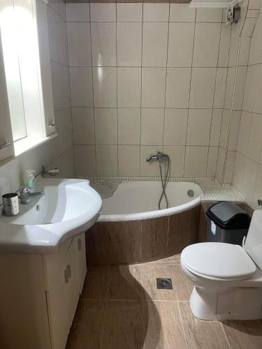 a bathroom with a tub and a toilet and a sink at mema apartment in Nea Peramos