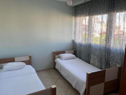 two beds in a room with a window at mema apartment in Nea Peramos