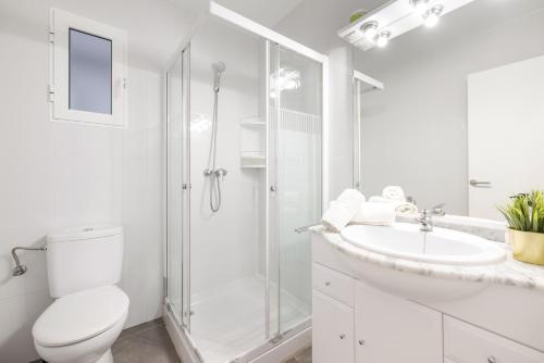 a white bathroom with a shower and a toilet and a sink at Apartament Platja L'arquitecte in L'Ampolla