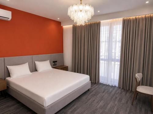 a bedroom with a white bed and a chandelier at Metropol Hotel Bishkek in Bishkek