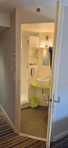 a small bathroom with a sink and a mirror at Kyriad Lyon Est - Saint Bonnet De Mure in Saint-Bonnet-de-Mure