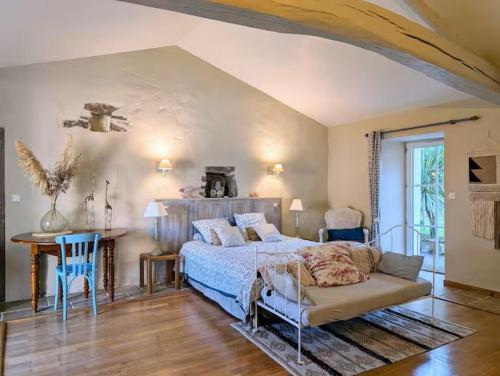 a bedroom with a bed and a desk and a table at Les Jardins de la Pinellerie in Vue