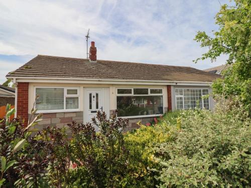 a red brick house with white windows and bushes at 6 Bastion Close in Prestatyn