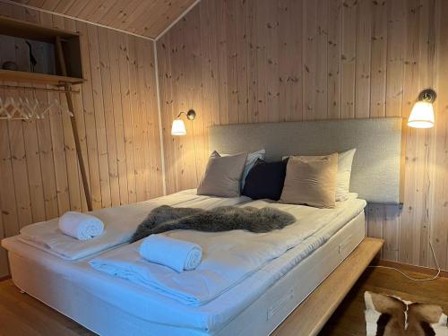 a large white bed in a room with wooden walls at Exclusive Designer Cabin - Panoramic Mountain View in Vossevangen