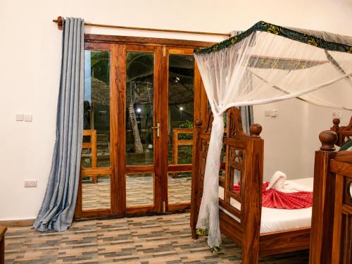 a bedroom with a wooden bed with a canopy at Jabali Bungalows Lodge in Paje