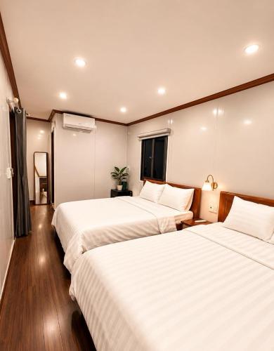 two beds in a hotel room with white sheets at ILLUMI Homestay in Dong Hoi