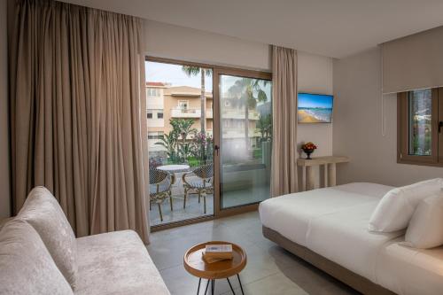 a hotel room with a bed and a balcony at Parthenis Hotel & Suites in Malia