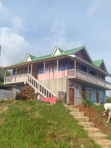 a house on a hill with a man in front of it at Pemazang Homestay in Sombāri