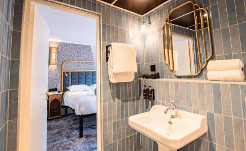 a bathroom with a sink and a mirror and a bed at Hôtel BOHEM, Sacré-Cœur in Paris