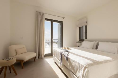 a bedroom with a bed and a chair and a window at Celestial Villas in Santa Maria