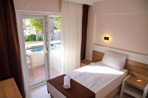 ein Schlafzimmer mit Bett und ein Balkon mit Pool in der Unterkunft Uraz Hotel in Kemer
