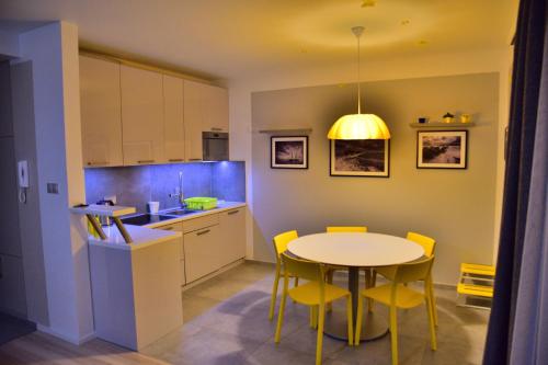 a kitchen with a table and yellow chairs in a room at Bajkowa Plaża - Muszelka in Gdańsk