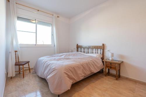 a bedroom with a bed and a window and a chair at ELS BALADRES in Deltebre