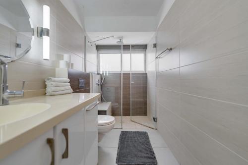 a white bathroom with a toilet and a shower at Spacious Luxury Beach Getaway by Torohome in Ashdod