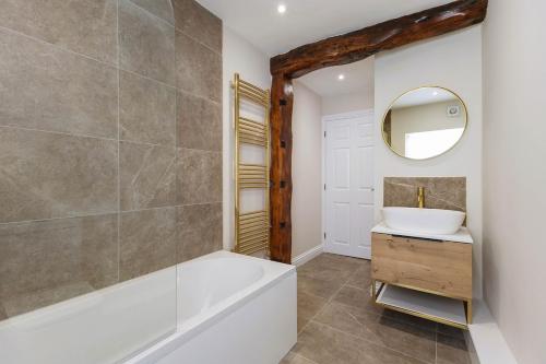 a bathroom with a tub and a sink and a mirror at Chic City Apartment in Wakefield