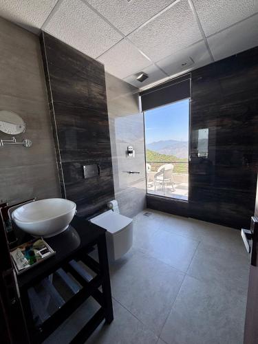 a bathroom with a sink and a toilet and a window at Rumuk Boutique Resort - Offbeat escape in Dhanaulti