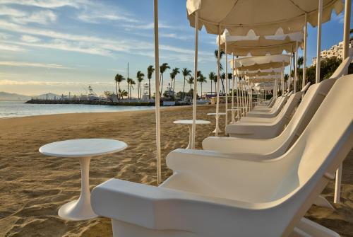 a row of white chairs and tables on the beach at Las Hadas by Brisas in Manzanillo