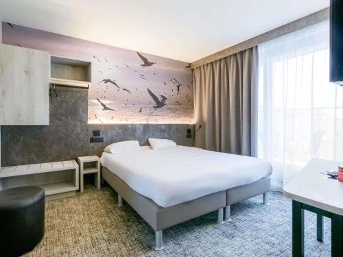 a hotel room with a bed with birds on the wall at ibis Styles Zeebrugge in Zeebrugge