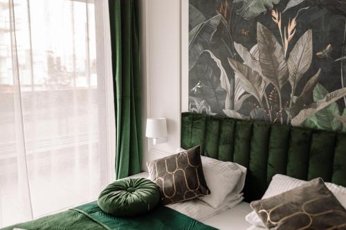 a green couch with pillows in a room with a window at GOLDEN HAUS Opole - Royal Blue & Royal Green in Opole