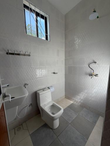 a white bathroom with a toilet and a sink at La luna di zanzibar in Kiwengwa