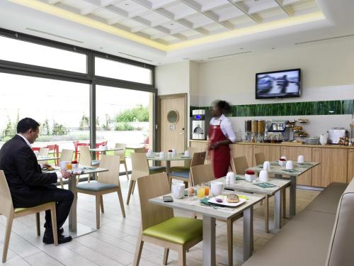 a man and woman sitting at tables in a restaurant at Aparthotel Adagio Paris Vincennes in Vincennes