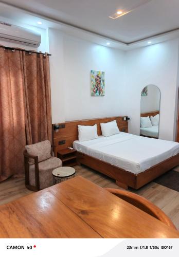 a bedroom with a bed and a chair and a table at Résidence saint Daniel in Cotonou
