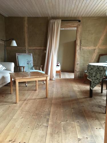 a living room with a wooden floor and a table at Charmante Ferienwohnung in einzigartiger Anlage - Büdnerei Lehsten in Möllenhagen