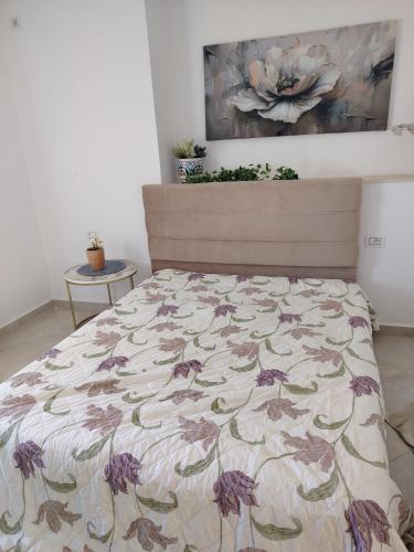 a bedroom with a bed with a floral bedspread at Kelibia ezzahra 2min a pied du plage in Ḩammām al Ghazzāz
