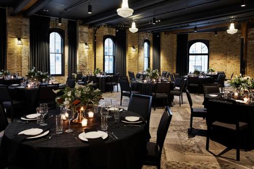 a dining room with tables and chairs and windows at Hewing Hotel in Minneapolis