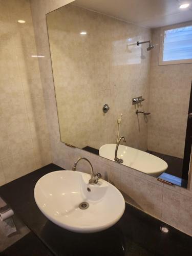 a bathroom with a sink and a mirror and a tub at Hotel Ikon in Hubli