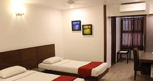 a hotel room with two beds and a desk at Hotel Ikon in Hubli