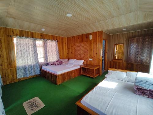 a bedroom with two beds and a green floor at Taray Heem Homestay in Ravangla